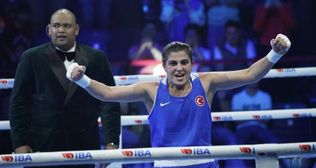 a woman in a blue tank top with arms raised in the air