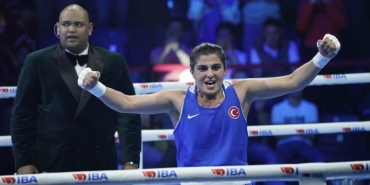 a woman in a blue tank top with arms raised in the air